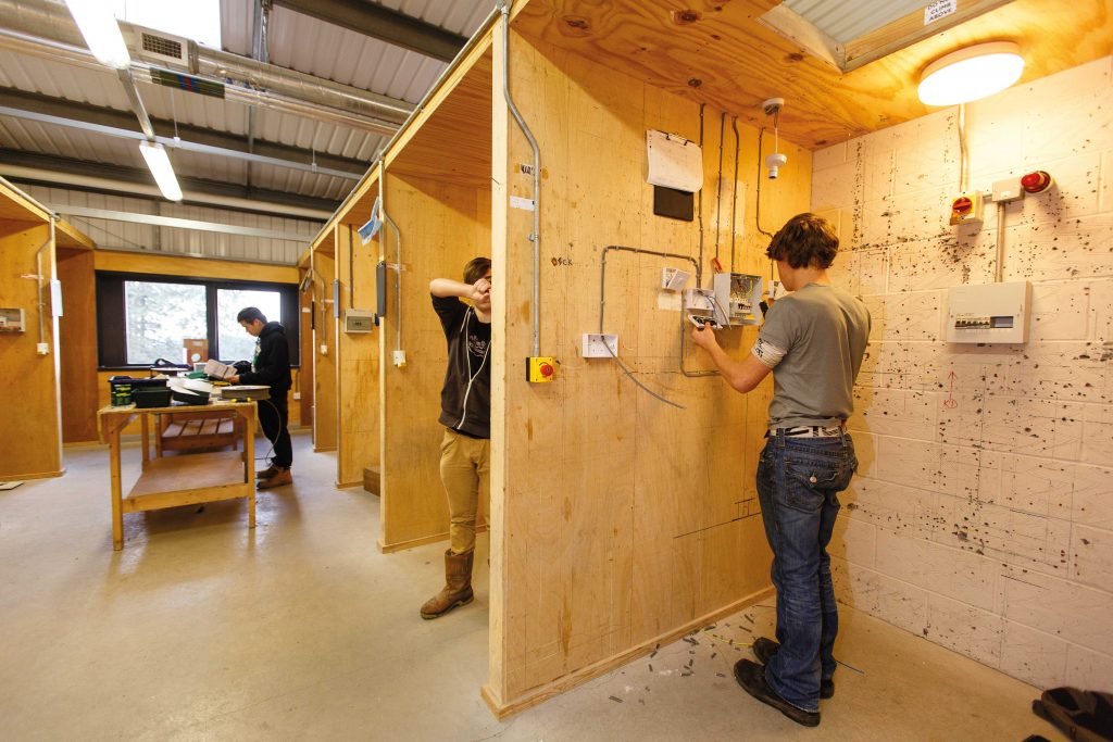 Electrical students standing in training bays
