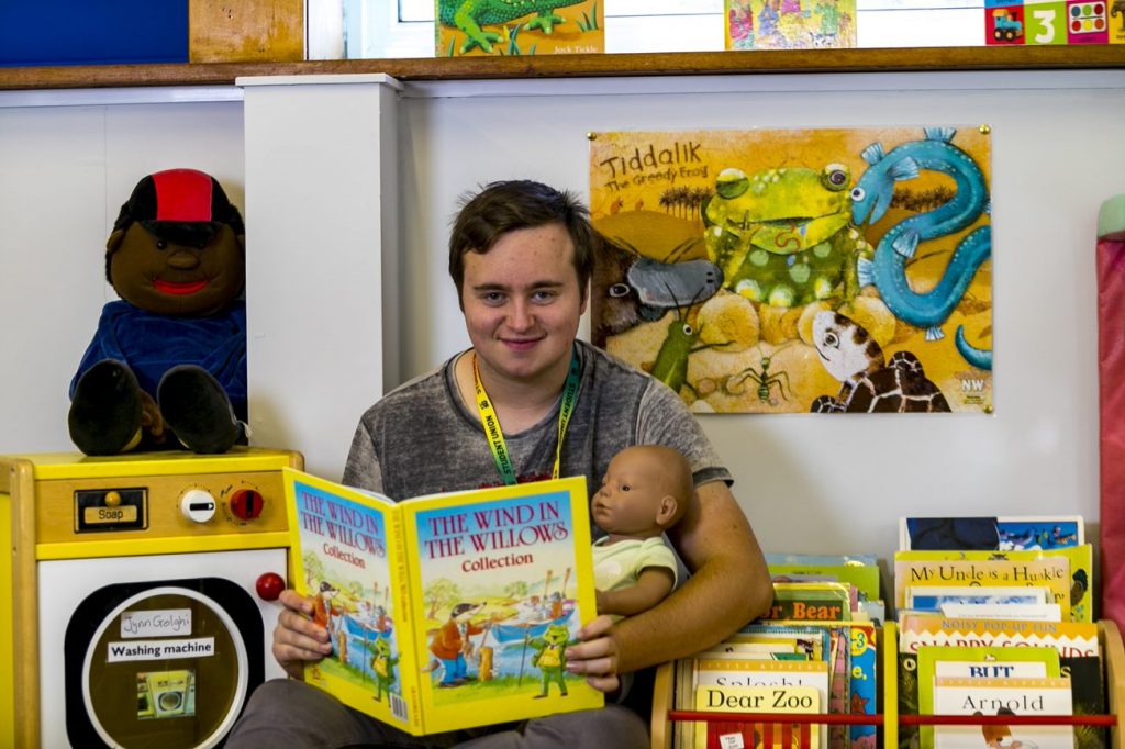 Childcare student holding a doll and a book