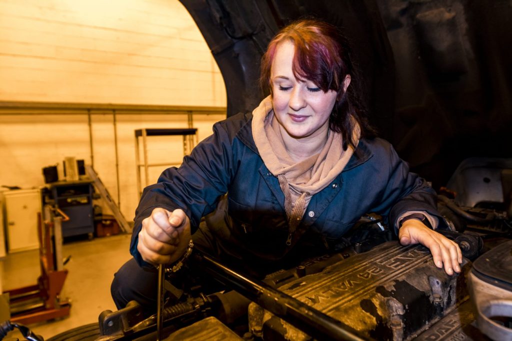 Female automotive student working on car 