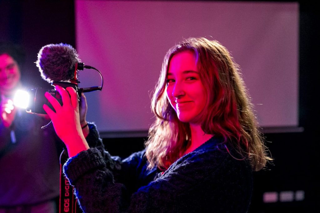 Female student holding a camera with a microphone