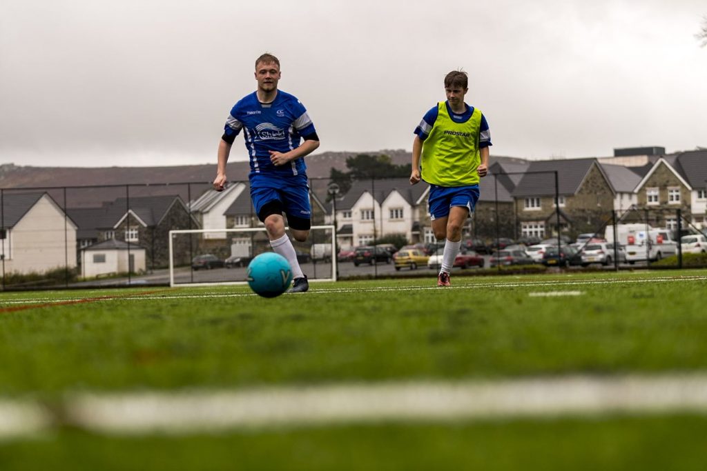 Two men playing football on pitch