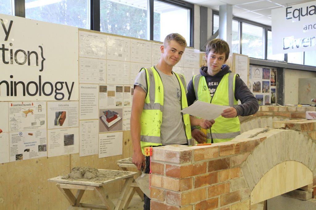 Two students building a wall in the construction workshop