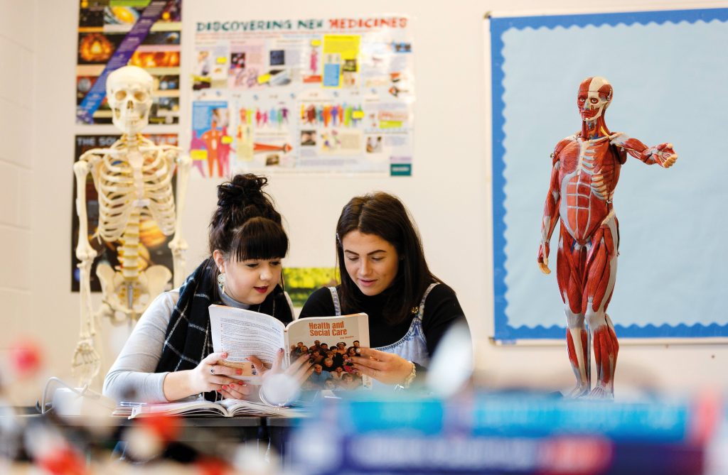 Two women reading book in classroom 