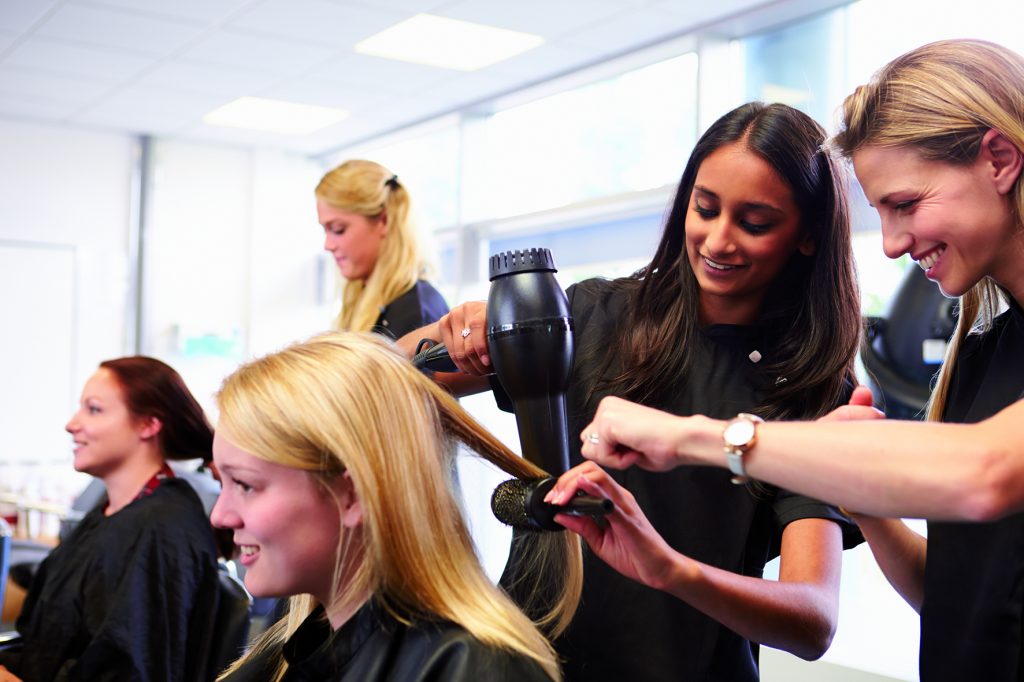 Teacher Helping Students Training To Become Hairdressers