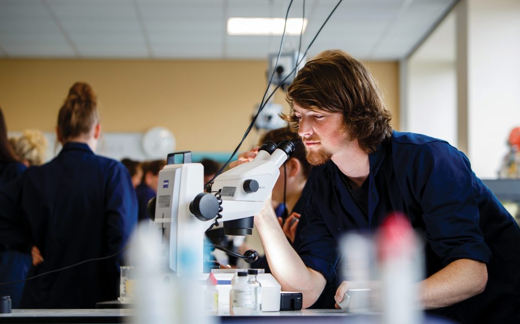 Man using microscope in classroom